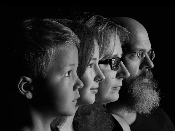Schwarz-weißes Familienportrait: vier Gesichter im Profil vor dunklem Hintergrund